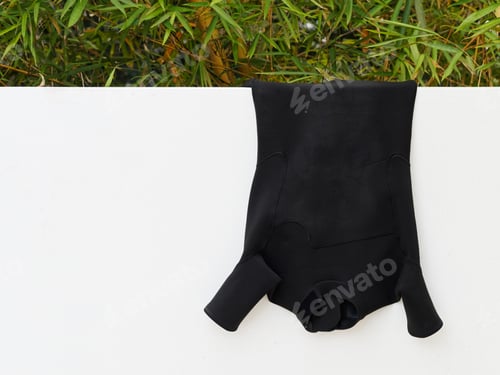 Preview: Black Surf Suit Drying On A White Wall.