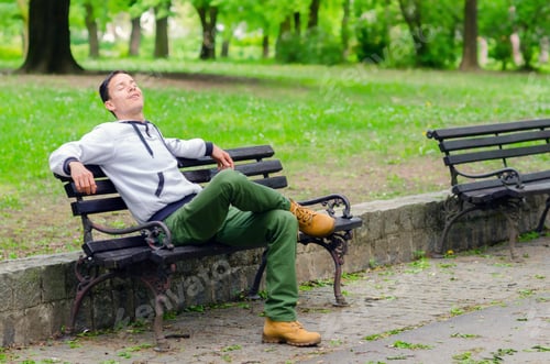 Preview: Young Man Sitting On The Bench In The Park And Enjoying Beautiful Spring Day.