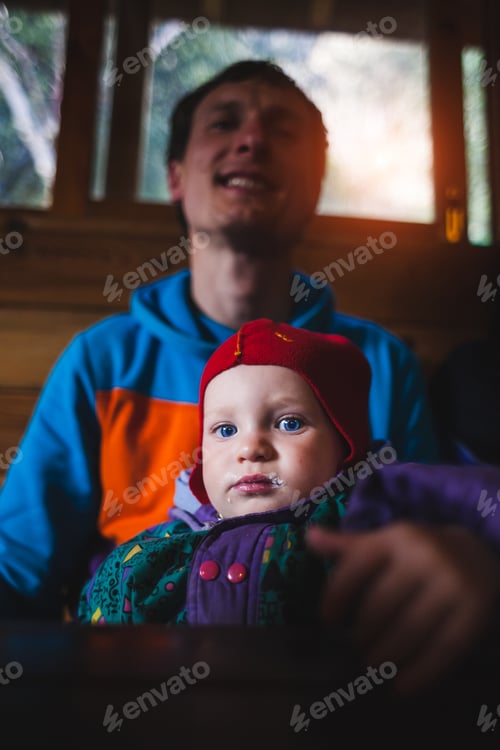 Preview: The Child Is Sitting With His Father In His Arms. Dad Feeds His Son. Portrait Of A Blue Eyed Kid. A