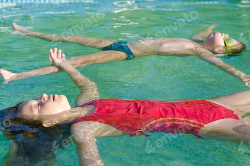 Preview: Little Boy And Little Girl Floating On The Water Surface Of The Swimming Pool On Sunny Summer Day.