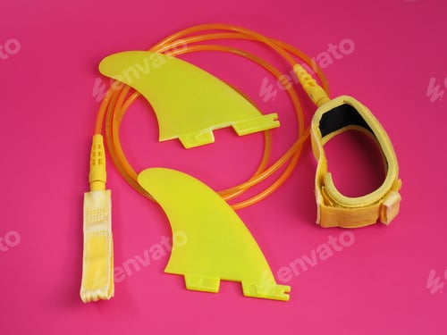 Preview: Yellow Surf Leash And Fins On Red Background.