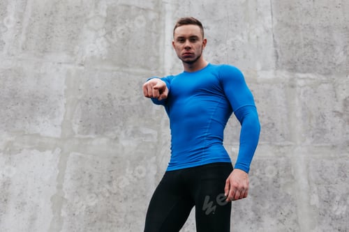 Preview: Portrait Of A Sporty Young Man In A Blue T-Shirt In Gray Wall Background