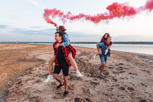 Preview: Group Of Young Friends Running Along The Beach And Holding Hand Flare Or Fusee. Freedom And