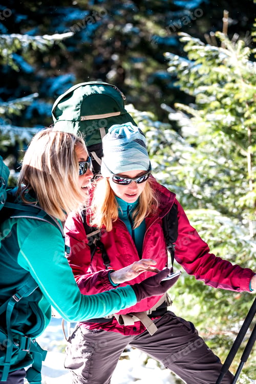 Preview: Two Tourists Look At The Phone. Two Friends Travel Together. Women With Backpacks In The Winter