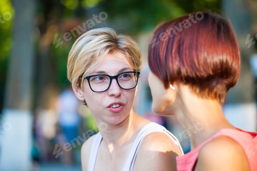 Preview: Two Young Women Sitting On A Park Bench And Smiling.