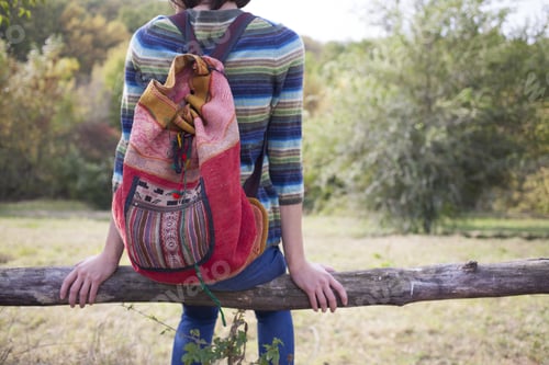 Preview: Girl With Backpack Sitting On The Fence And Looking At Nature.