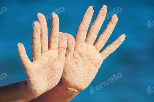 Preview: Woman Show'S Hands Covered With Sand On A Blue Sea Background.