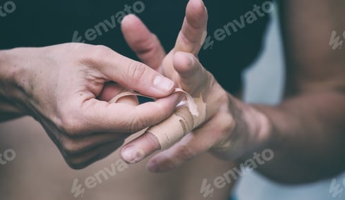 Preview: Rock Climber Wraps Fingers With Tape. Female Hands Closeup. Protection Against Damage. Athlete