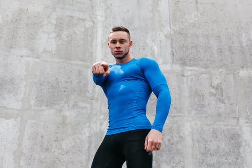 Preview: Portrait Of A Sporty Young Man In A Blue T-Shirt In Gray Wall Background
