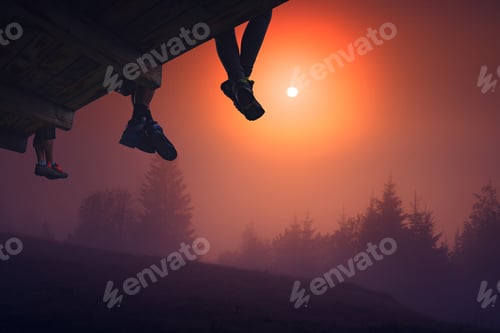 Preview: Hikers Sit On A Wooden Flooring Above The Valley Covered With Fog. Early Morning Time.
