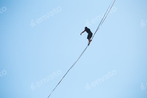 Preview: A Man Walks Along The Highline Against The Blue Sky. Highliner Goes On A Stretched Sling. Tightrope