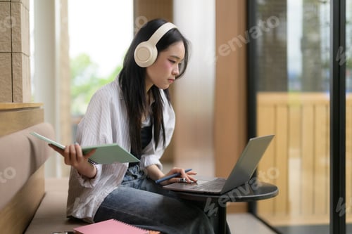 Preview: Young woman learning online with laptop and headphones