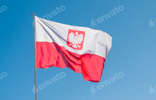 Preview: Polish flag with coat of arms waving on a flagpole against a clear blue sky.