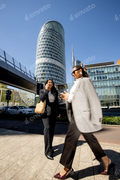 Preview: Business professionals walking in a city with modern buildings during a sunny day