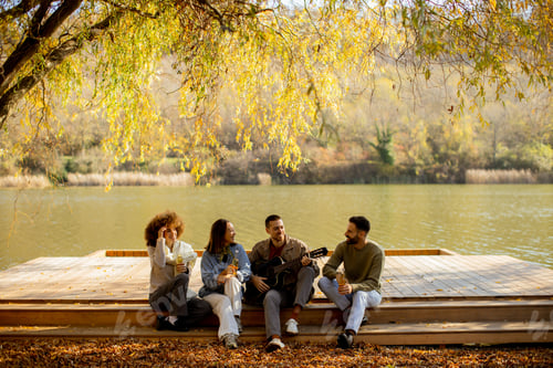 Preview: Friends enjoying a relaxing afternoon by the lake while playing music and sharing laughter