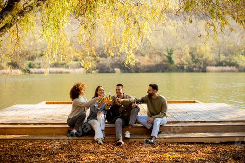 Preview: Friends enjoy a sunny afternoon by the lake with music and laughter in autumn
