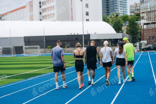 Preview: Group of athletes walking on blue running track