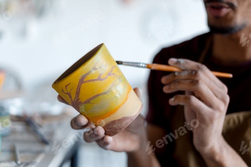 Preview: Artist painting terracotta pot in a ceramics studio