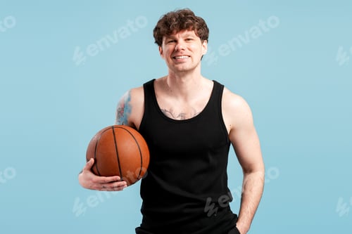 Preview: Young man smiling holding basketball on blue background