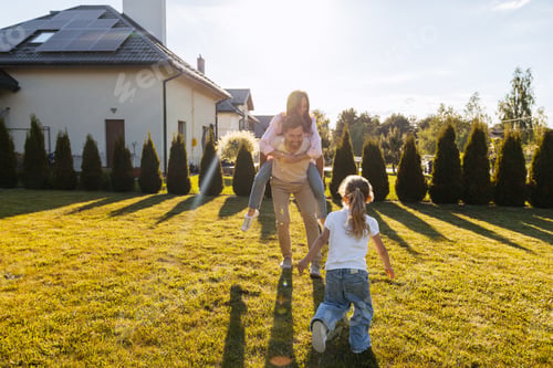 Preview: Happy family playing together in backyard with solar panels