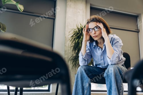 Preview: Woman experiencing stress, headache, and burnout in office