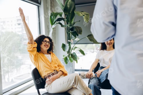 Preview: Smiling woman raising hand during business meeting or seminar