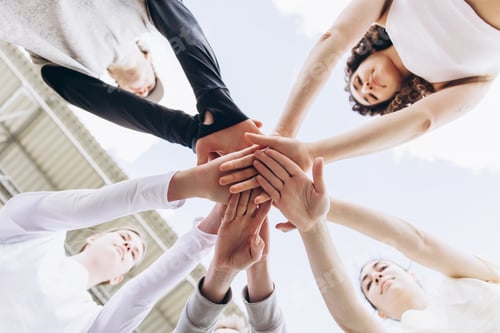 Preview: Group of diverse people putting hands together showing teamwork
