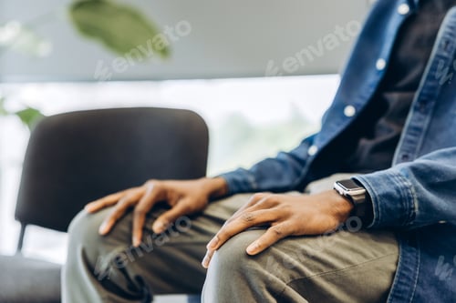 Preview: Man waiting patiently with hands resting on lap selective focus on hands
