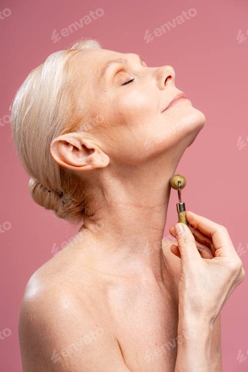 Preview: Senior woman doing neck massage with a jade roller