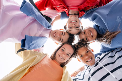 Preview: Diverse teenagers smiling forming a huddle looking down