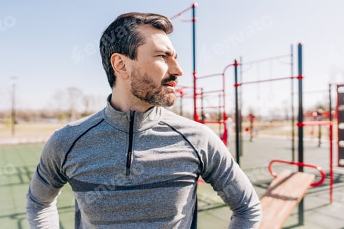 Preview: Confident man standing in outdoor gym after workout