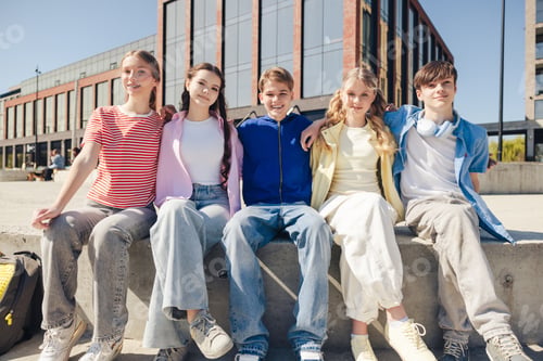 Preview: Diverse group of smiling positive teen girls and boys hugging looking at camera on the street