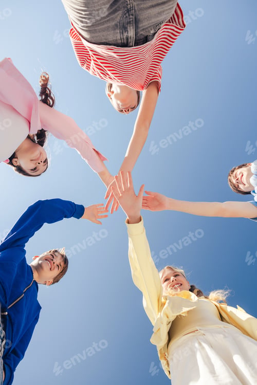 Preview: Smiling teenage boys and girls standing together with hands joined as team