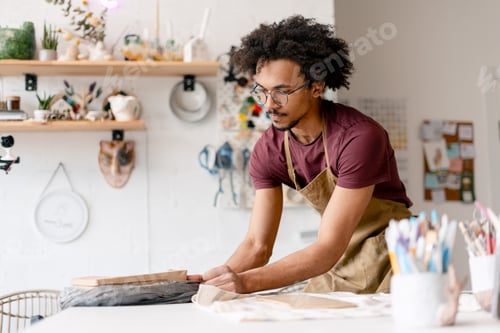 Preview: Young man working in pottery studio preparing packaging