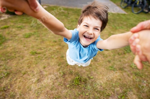 Preview: Happy boy spinning outdoors holding parent's hands