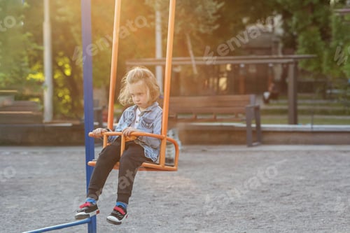 Preview: Sad boy sitting on swing at playground