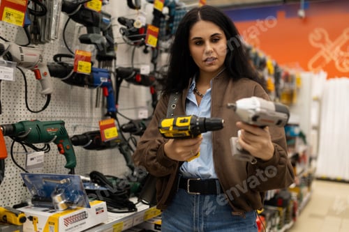 Preview: Woman choosing between different power tools in a retail hardware store