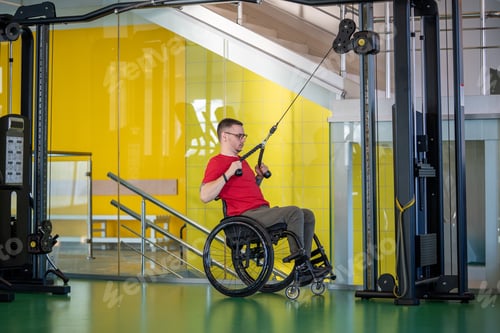 Preview: Motivated strong disabled man training upper body muscles with sports training machine for therapy