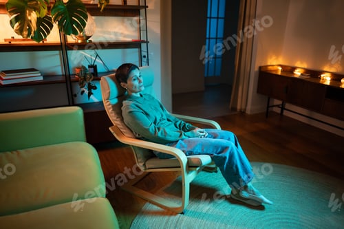 Preview: Thoughtful senior woman sitting alone in room in rgb light, coping with loneliness after divorce.