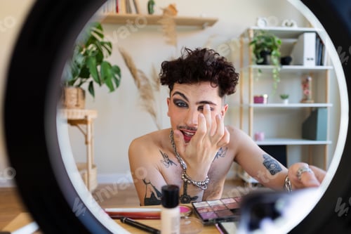 Preview: Person applying dramatic makeup looking at ring light