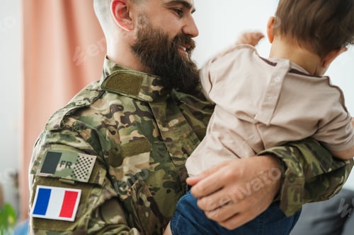 Preview: Smiling Soldier in Camouflage Uniform Holding a Toddler at Home