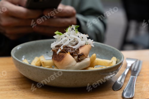 Preview: Modern cafe lunch meal featuring a gourmet meat roll and golden french fries in a ceramic dish