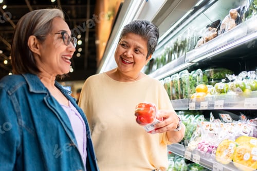 Preview: Two cheerful Asian senior women shopping for groceries in a supermarket.