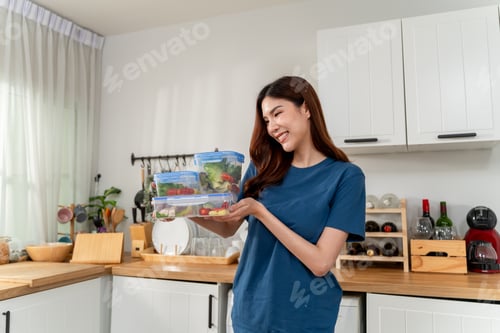 Preview: Smiling Woman Holding Healthy Meal Prep Containers in a Bright Kitchen