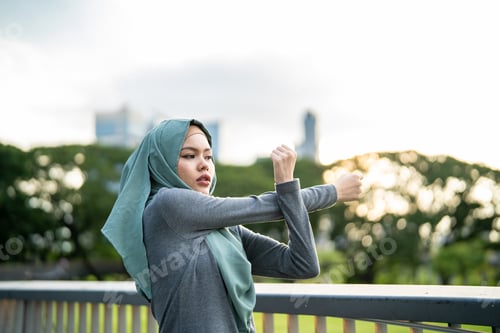 Preview: Asian Muslim woman stretching body while exercise on the rooftop garden.