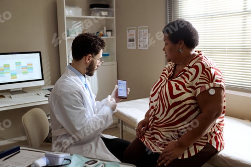 Preview: Black Woman Reviewing Glucose Monitoring App with Doctor during Checkup