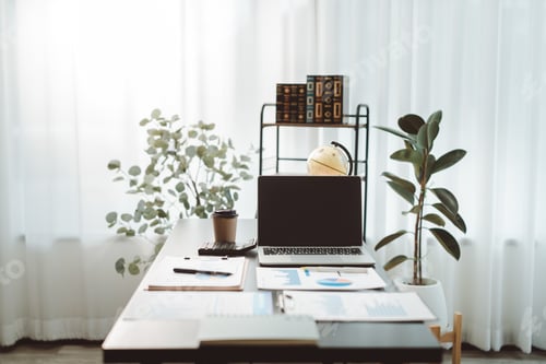Preview: Modern desk setup in a bright home office featuring a laptop, business reports, calculator, and coff