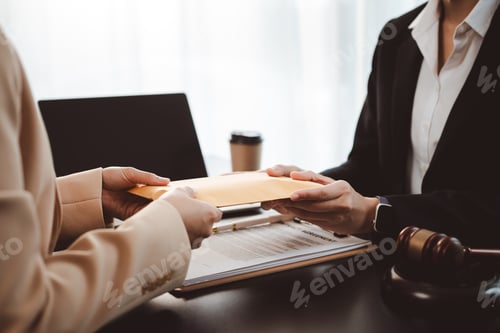 Preview: Businesswoman handing brown envelope containing document or money to a lawyer during a legal consult