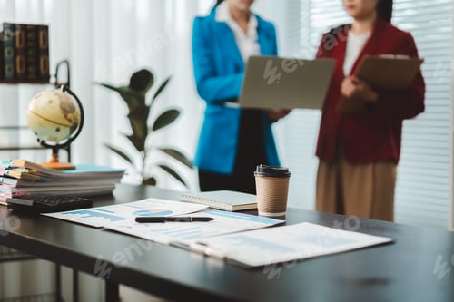 Preview: Businesswomen analyzing financial data and corporate strategy in a modern office, standing together