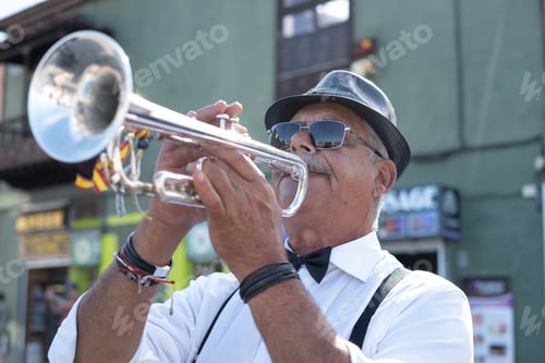 Preview: Mature adult street musician playing a trumpet, wearing a fedora, sunglasses, white shirt, bow tie,